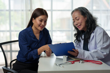 Asian elderly doctor explaining Advising Asian female patients about medicines in hospital Asking about illness history Health check and encouragement health insurance concept.