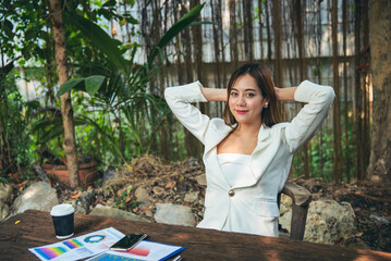 Woman streching arm raised sitting incorrect position home office desk. Back side of young asian...