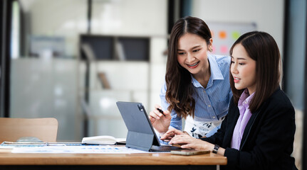 Two happy businesswomen coworking with a laptop in a desktop at office
