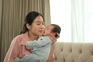 Loving mother with newborn baby boy hugging and kissing gently. Motherhood and childcare concept