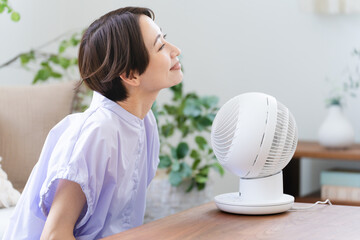 サーキュレーターで涼しむ若い女性　ライフスタイルイメージ