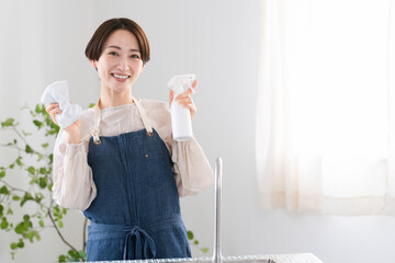 キッチンを掃除するエプロン姿の女性　ライフスタイルイメージ