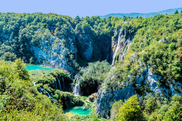 Scenic view of cascading waterfalls and turquoise lakes surrounded by lush green vegetation and cliffs, in Croatia