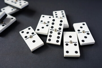 white domino blocks on black background. There are some benefits of playing domingo; helps to develop critical thinking skills, bond with families and social groups, reduces stress, improve memory.
