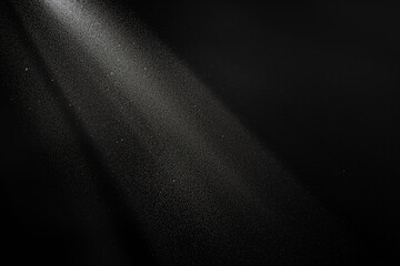 Bright white light beam shining through falling snow on black background