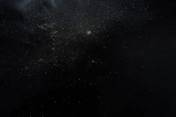 Fototapeta premium White particles floating on a black background