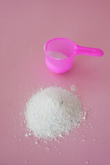 Washing powder in plastic spoon on table 