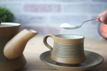 pouring white sugar in a tea cup 