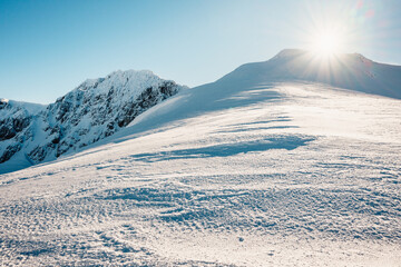 Alpine mountains landscape with white snow and blue sky. Sunset winter in nature. Frosty trees under warm sunlight. Wintry landscape. Low Tatras, Dumbier, Slovakia