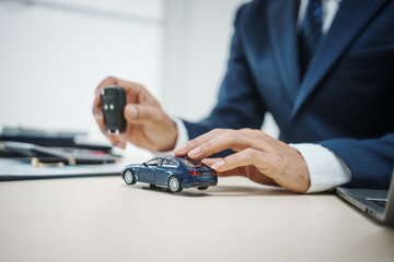 A man in a suit works at his desk selling cars and online car insurance with low interest rates, offering car loans, vehicle financing, and comprehensive vehicle coverage