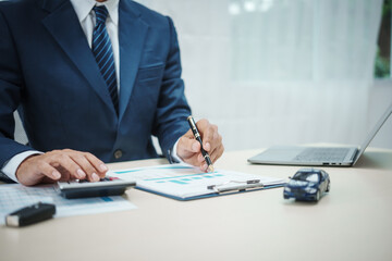 A man in a suit works at his desk selling cars and online car insurance with low interest rates, offering car loans, vehicle financing, and comprehensive vehicle coverage
