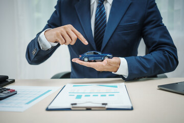 A man in a suit works at his desk selling cars and online car insurance with low interest rates, offering car loans, vehicle financing, and comprehensive vehicle coverage