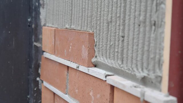 A bricklayer is seen applying mortar on a wall as part of the building construction process