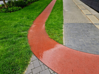 Obraz premium running route made of red rubber material. year-round soft circuit for training in the office district parallel to the sidewalk.