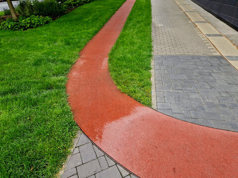 running route made of red rubber material. year-round soft circuit for training in the office district parallel to the sidewalk.