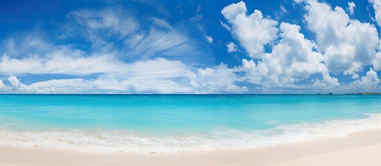Fototapeta premium Panoramic view of a stunning beach with white sand, turquoise waters, and a sunny blue sky with clouds, ideal backdrop for a summer vacation. Copy space image