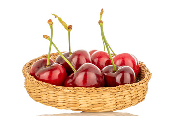 A few sweet cherries in a straw plate, macro, isolated on a white background.
