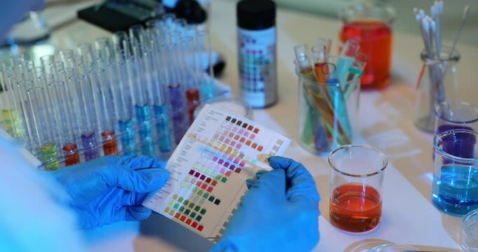 Chemist compares colors on paper strip with control palette