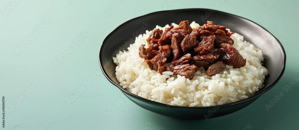 Poster Steamed rice topped with fried beef on black plate isolate on pastel background. with copy space image. Place for adding text or design