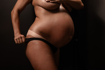 Naklejka premium Pregnant woman pulls back her panties showing instant tan. Vertical photo. 