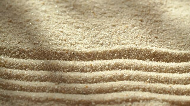 Close-up making sand zen garden using mini wooden rake with shadows and sunlight