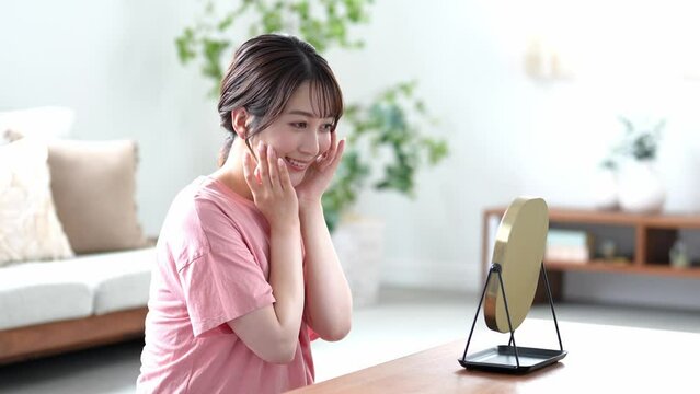 家のリビングで鏡を見る若い日本人女性