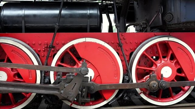 Front view of a steam locomotive wheels at a railway station.