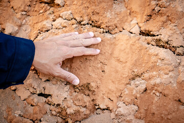 Geotechnical engineering concept. Male hand of soil engineer in reflective green vest inspecting sample of laterite soil for construction improvement base road work