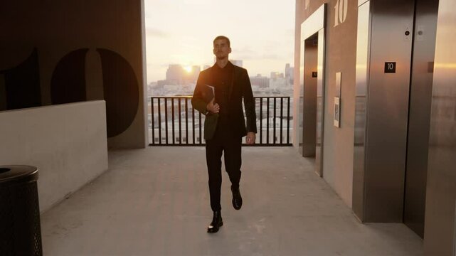 A young businessman confidently walks with a tablet in a modern urban setting at sunset, showcasing professionalism and ambition against city skyline, reflecting a determined career mindset