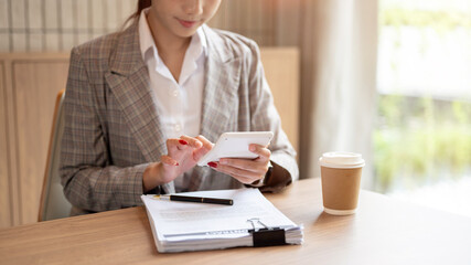 A cropped image of an Asian businesswoman using a calculator at a table.