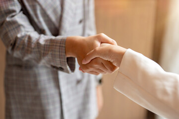 A close-up image of a businesswoman is shaking hands with her colleague in the meeting. teamwork