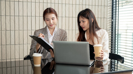 Two attractive Asian businesswomen are discussing work and working together in the meeting room.