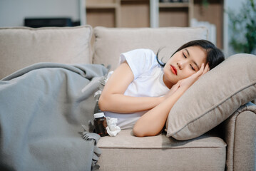 Fototapeta premium Asian woman sit Depression Dark haired pensive glance Standing by window and anxiety Copy space with a blanket on a sofa.