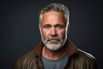 Obraz premium A man with a beard and gray hair is wearing a brown jacket and a gray shirt