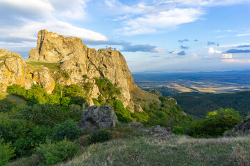 View of the Kojori fortress on the rock from the neighboring mountain. The evening sun illuminates the stone walls