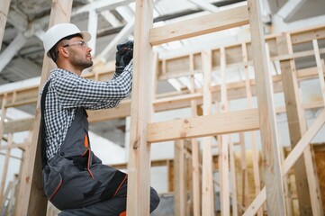 Portrait of a young carpenter worker in a helmet at the construction site of modular houses