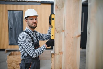 Portrait of a young carpenter worker in a helmet at the construction site of modular houses