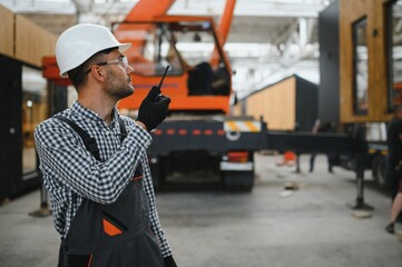 Foreman manages the loading of a prefabricated modular house to truck using walkie talkie