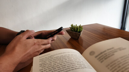 Side view, a man's hand hold a smartphone. Corner space at cafe background with copy space.