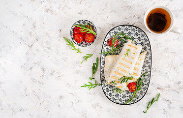 Tasty breakfast with lavash. Mexican cuisine. Trending food with pita bread, cheese, tomatoes and spinach. Top view