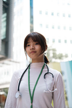 Smiling young doctor with stethoscope standing in front of glass