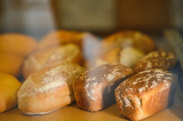 Freshly baked bread on bakery shelves. Bread diversity in bright light. Breads with a golden crust on wooden shelves