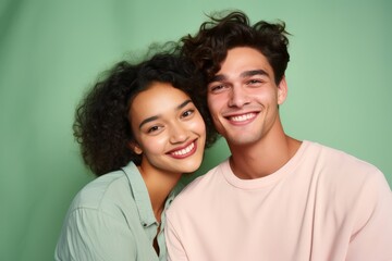 Fototapeta premium Portrait of a young couple, age 20, Mixed race, looking happy, first love, pastel mint background