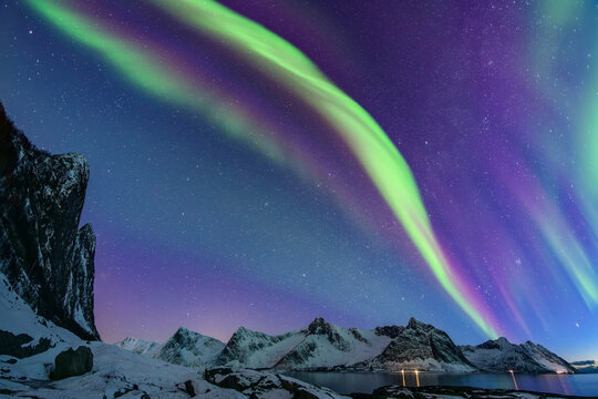 Snowcapped mountains and sea under aurora polaris at Senja island, Troms, Norway