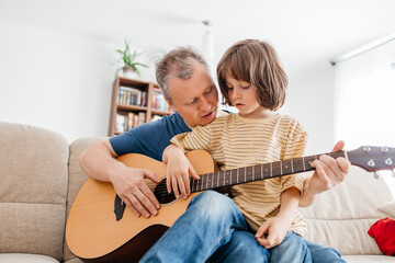 Son learning guitar with father at home