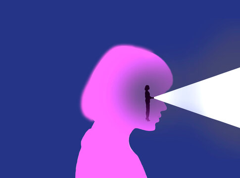 Woman shining flashlight through eyes of oversized womans head
