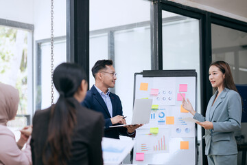 in corporate offices in Asia Business woman and man, they work together to plan a project. Analyze charts on laptop and discuss creative ideas with confidence and happiness.