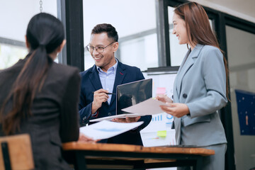 in corporate offices in Asia Business woman and man, they work together to plan a project. Analyze charts on laptop and discuss creative ideas with confidence and happiness.