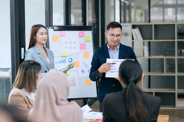 in corporate offices in Asia Business woman and man, they work together to plan a project. Analyze charts on laptop and discuss creative ideas with confidence and happiness.