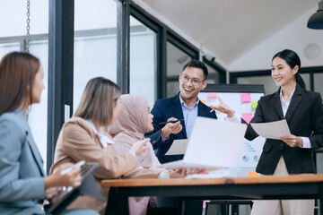 Professional business people taking part in a business meeting Discussing finances, strategies, and investing, they analyze charts on laptops. Demonstrate teamwork and effective communication.
